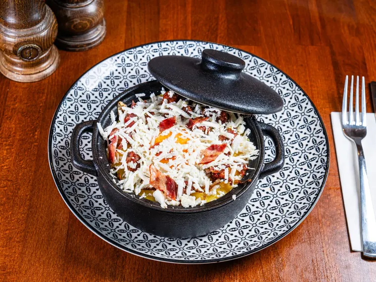 A plate of hearty bulz (baked polenta with cheese) with egg and smoked meats, at Ciorbe La Ion