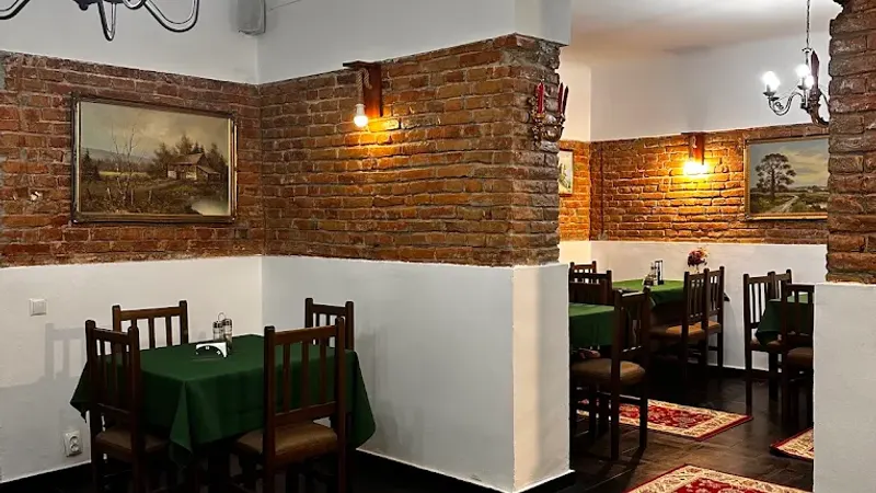 A corner of the dining room with brick walls, paintings and tables in green linen