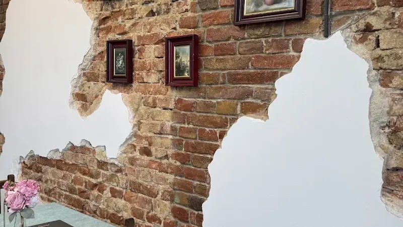 An exposed brick wall hung with small framed paintings