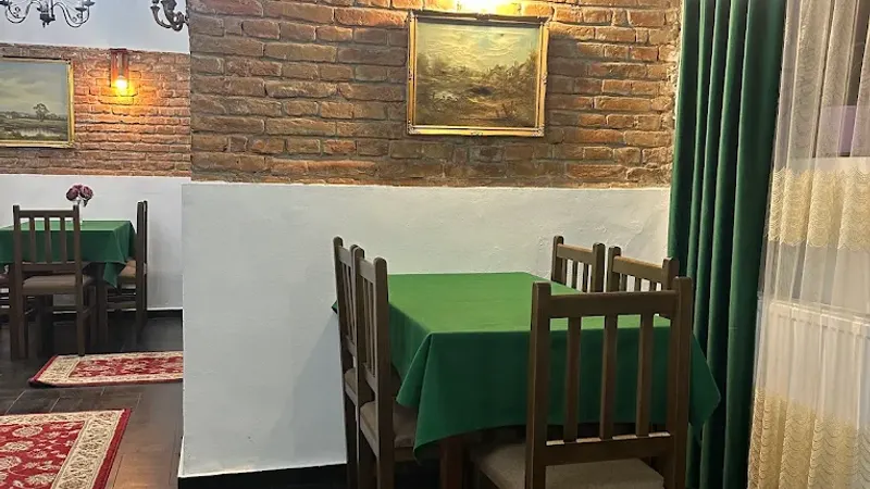 A table in green linen beside a brick wall, under framed paintings