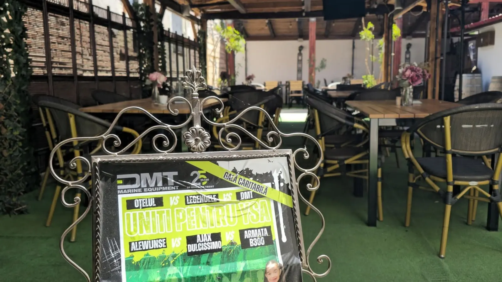 Free tables on the terrace, with a poster on a wrought iron stand