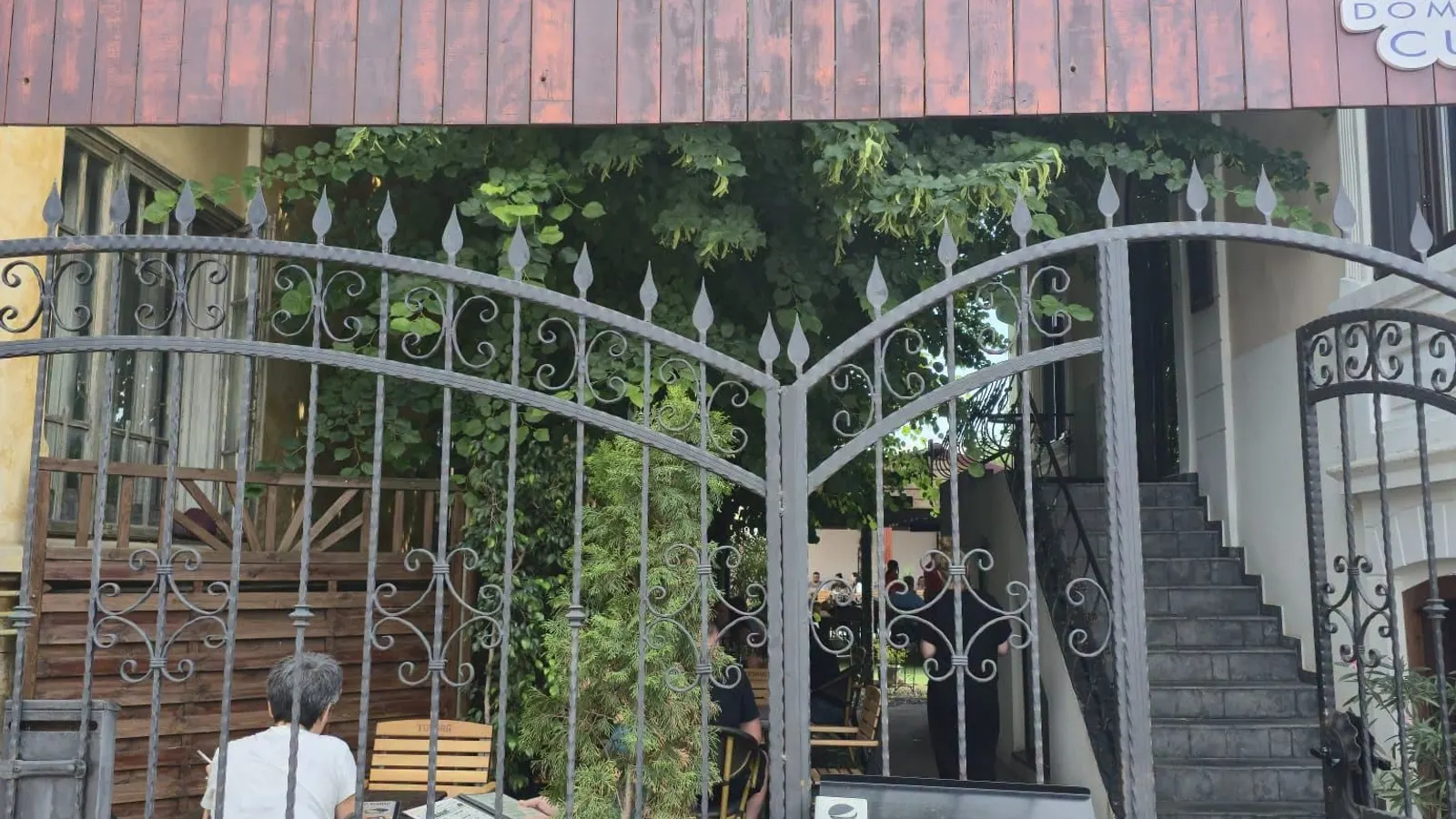A wrought iron gate towards the terrace courtyard, shaded by greenery